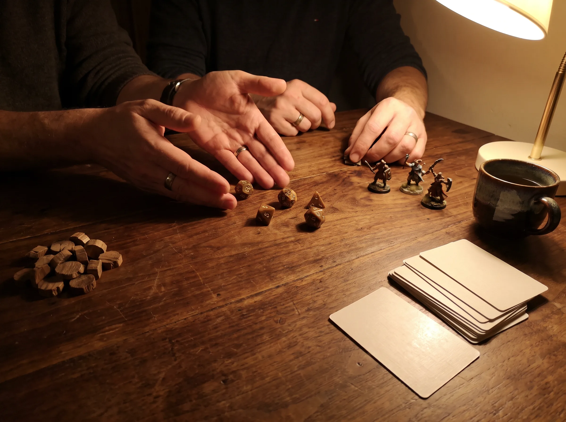 Hands rolling dice beside miniatures